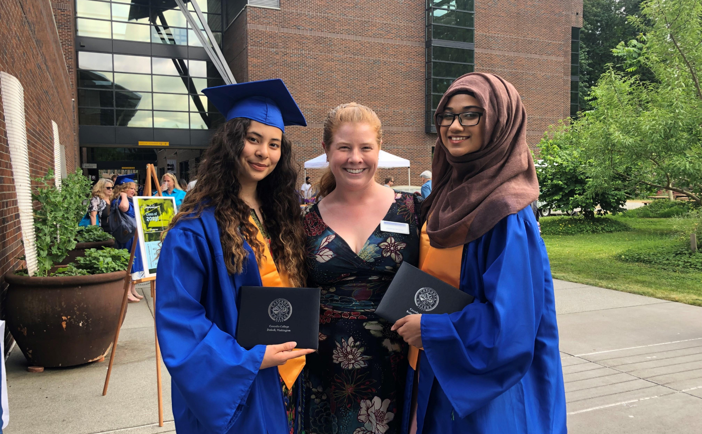 A Cascadia staff member poses with two graduating students